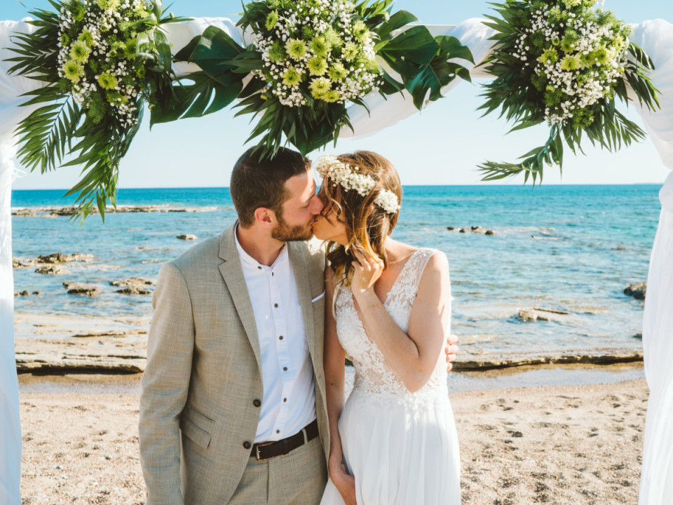 Hochzeitspaar küssend bei Hochzeitszeremonie am Strand
